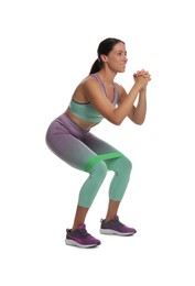 Woman doing squats with fitness elastic band on white background