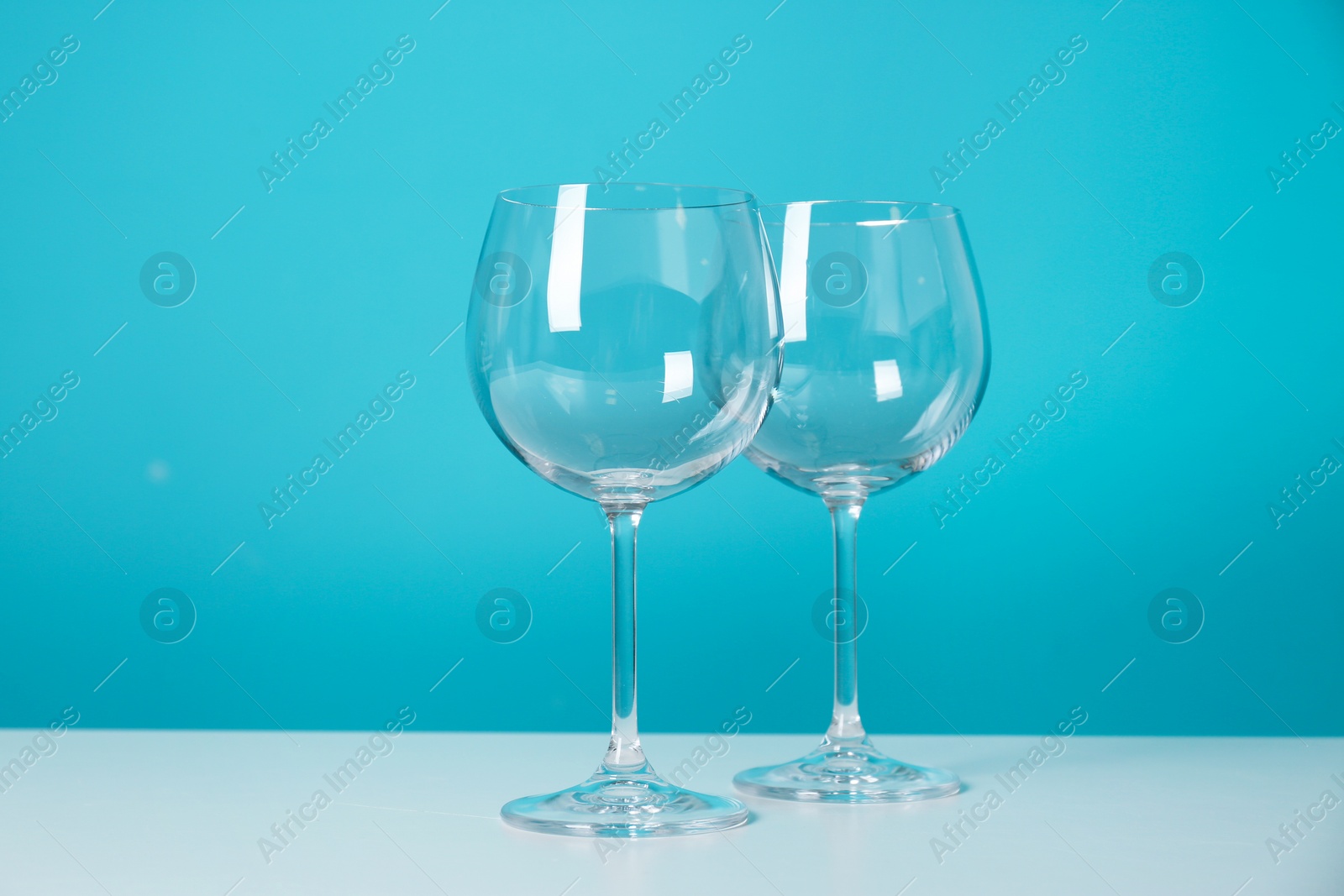 Photo of Clean wine glasses on table against color background