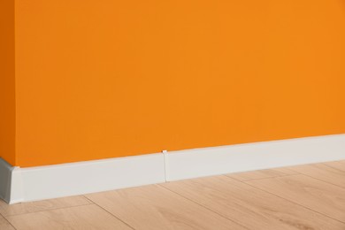 Photo of Orange wall and laminated floor in office room. Interior design