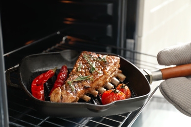 Chef taking delicious roasted ribs out of oven, closeup