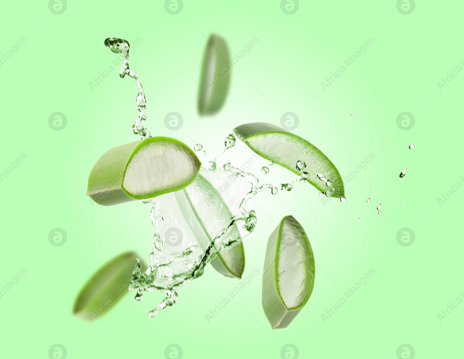 Image of Sliced aloe vera leaf and splashes of juice on green background