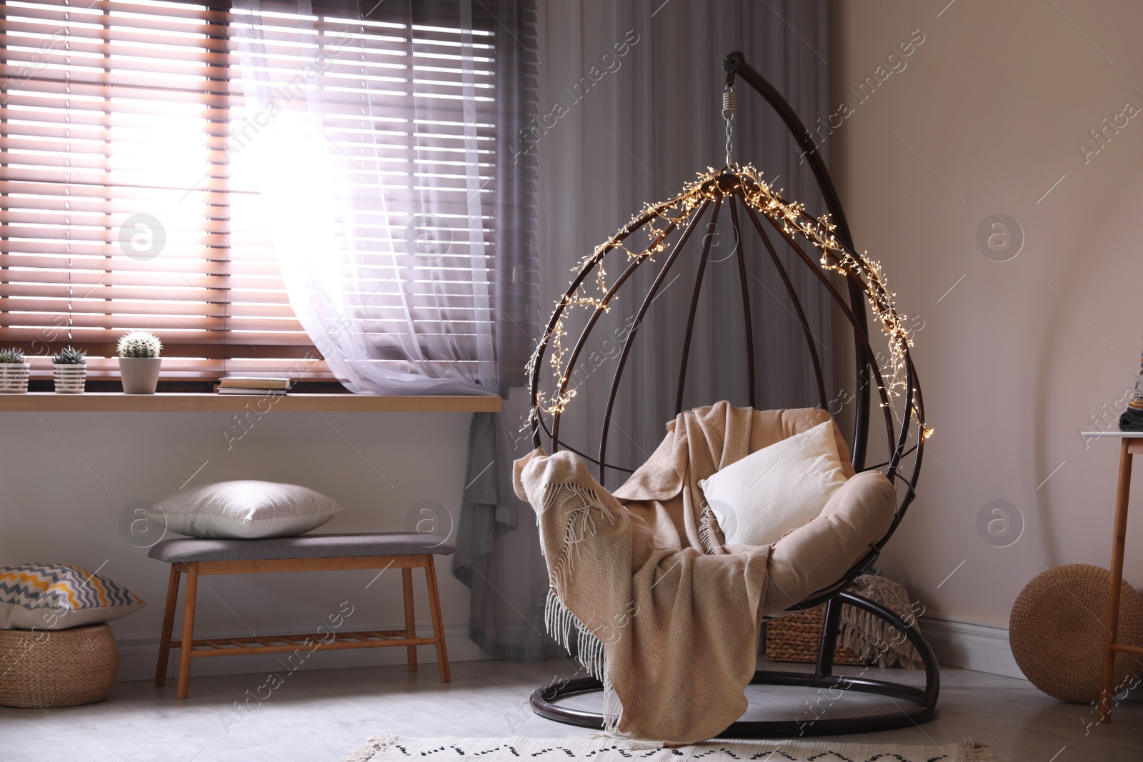 Photo of Cozy hanging chair with fairy lights in modern living room. Interior design