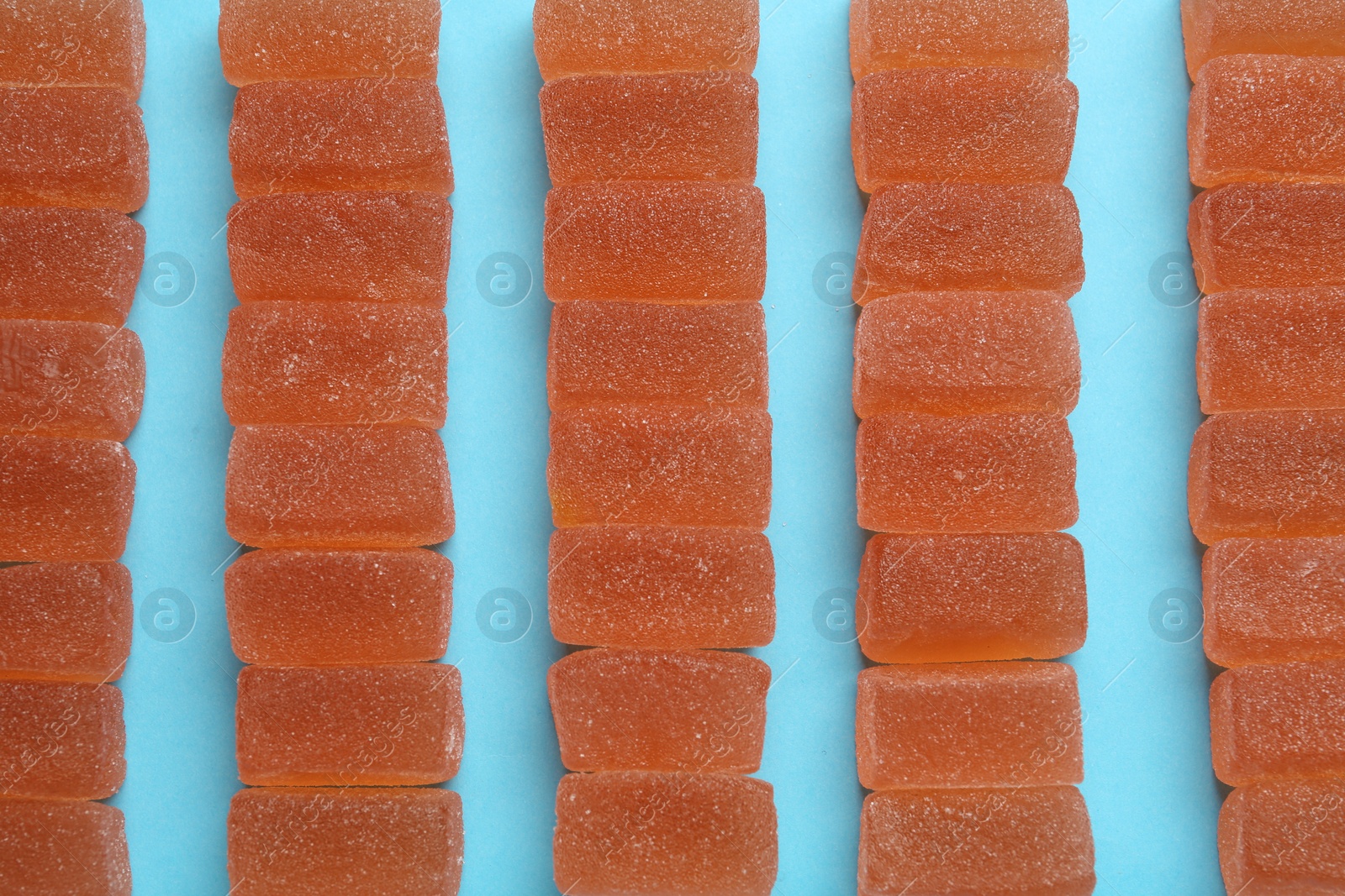 Photo of Tasty orange jelly candies on light blue background, flat lay
