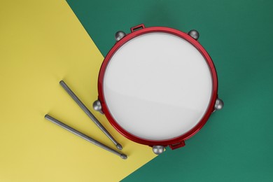 Photo of Children's drum with drumsticks on color background, top view