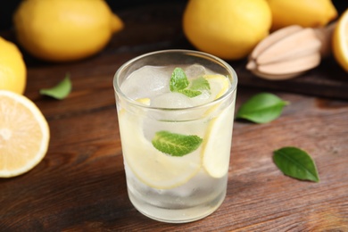 Cool freshly made lemonade in glass on wooden table, closeup