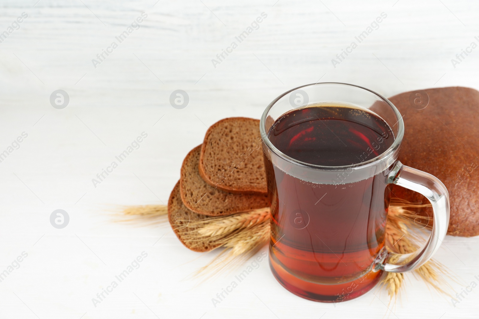Photo of Composition with delicious kvass, spikes and bread on white table. Space for text