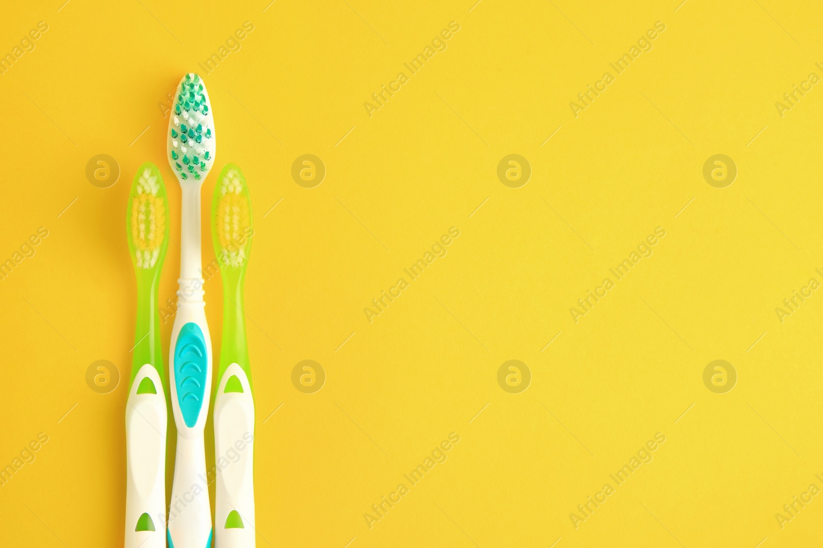 Photo of Toothbrushes on yellow background, flat lay. Space for text