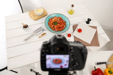 Photo of Professional camera and composition with spaghetti on table in studio. Food stylist