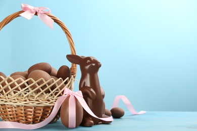 Chocolate Easter bunny and eggs on light blue wooden table. Space for text