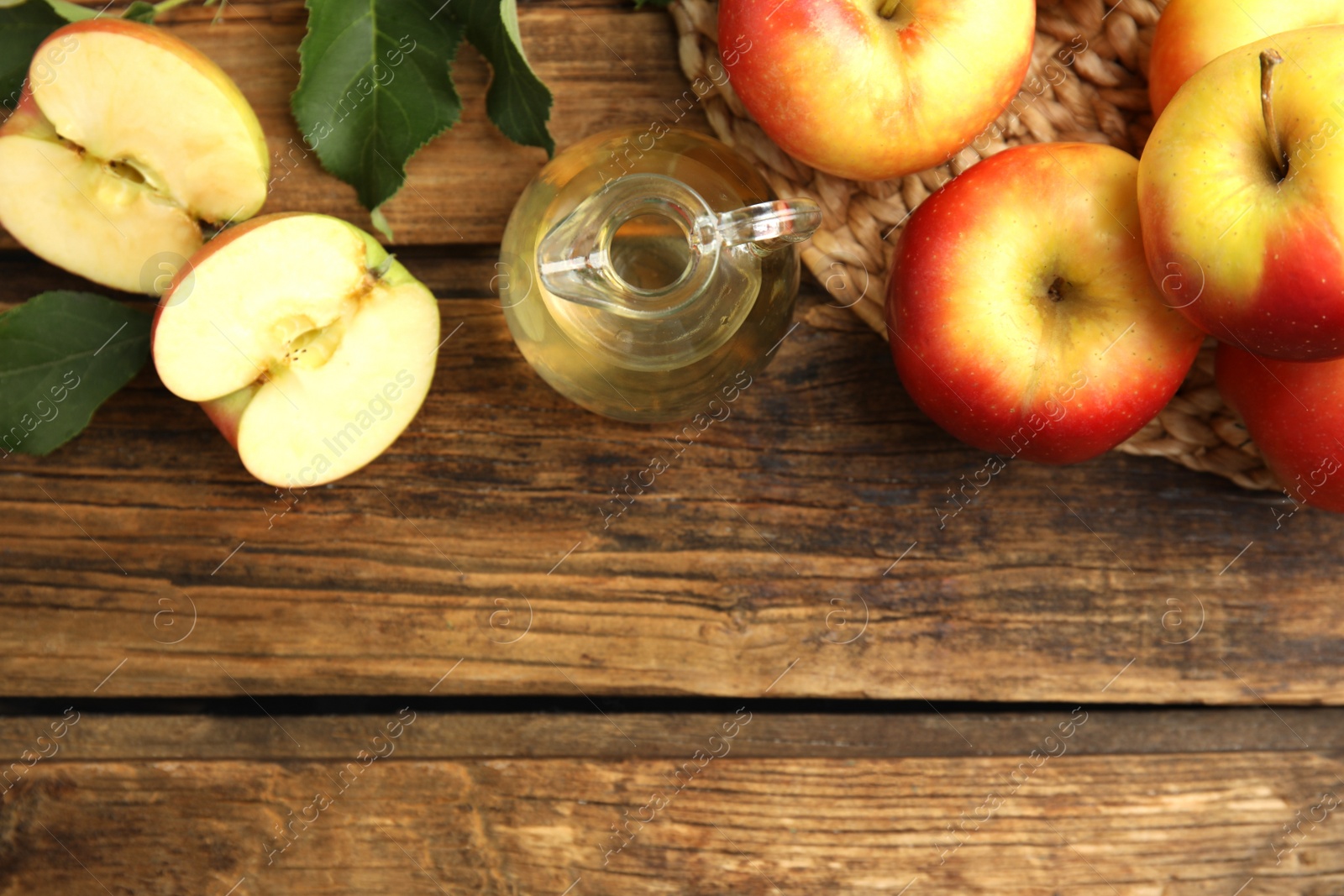 Photo of Natural apple vinegar and fresh fruits on wooden table, flat lay. Space for text