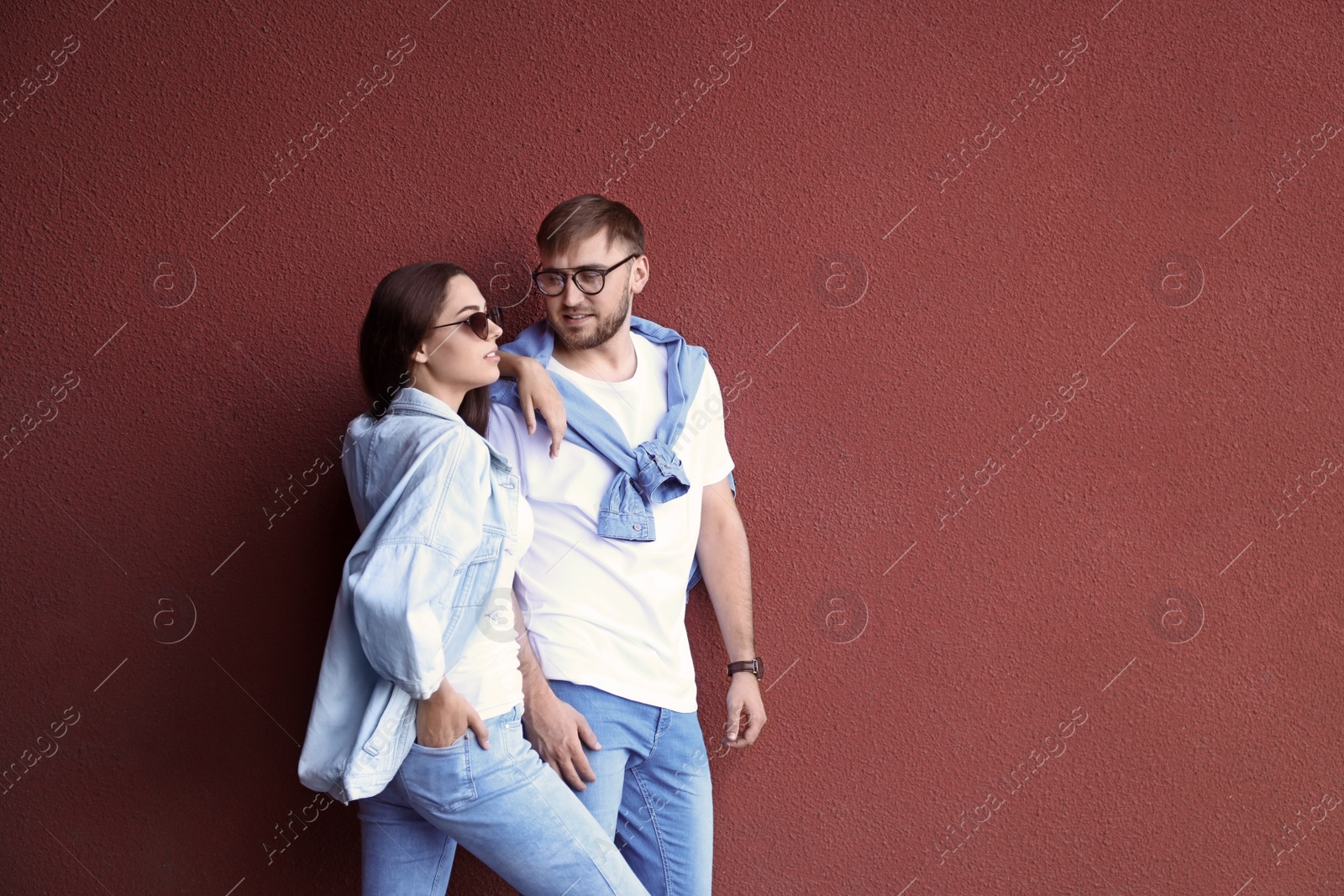 Photo of Young hipster couple in stylish jeans posing near color wall