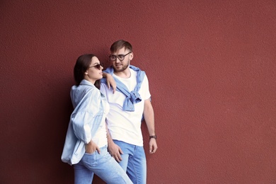 Young hipster couple in stylish jeans posing near color wall