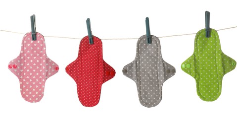 Many different cloth menstrual pads hanging isolated on white