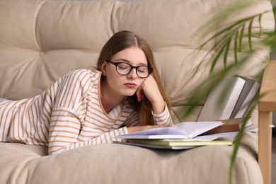 Photo of Young tired woman studying on beige couch