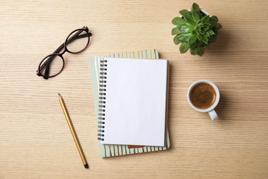 Photo of Flat lay composition with notebooks, coffee and glasses on wooden background