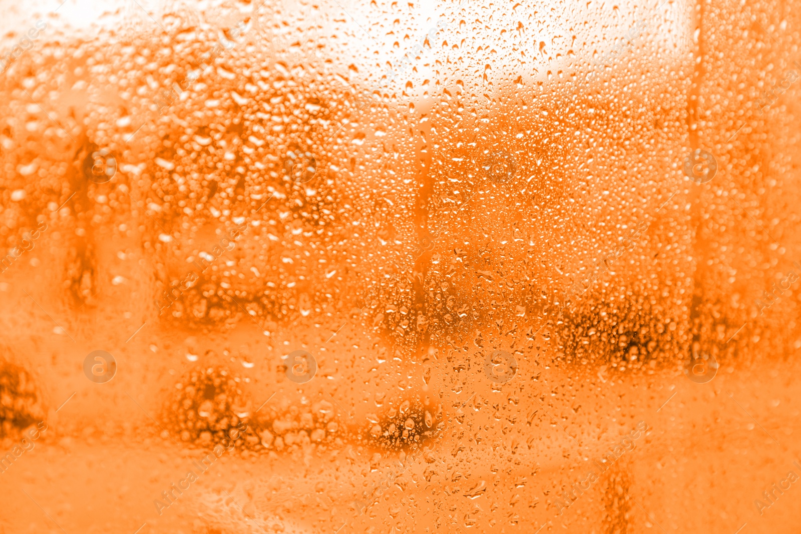 Image of Closeup view of foggy window with rain drops. Toned in orange