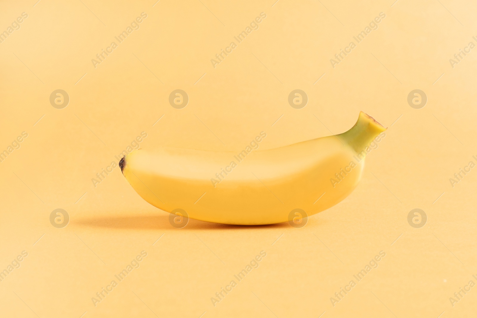 Photo of One sweet ripe baby banana on light orange background