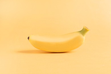 One sweet ripe baby banana on light orange background
