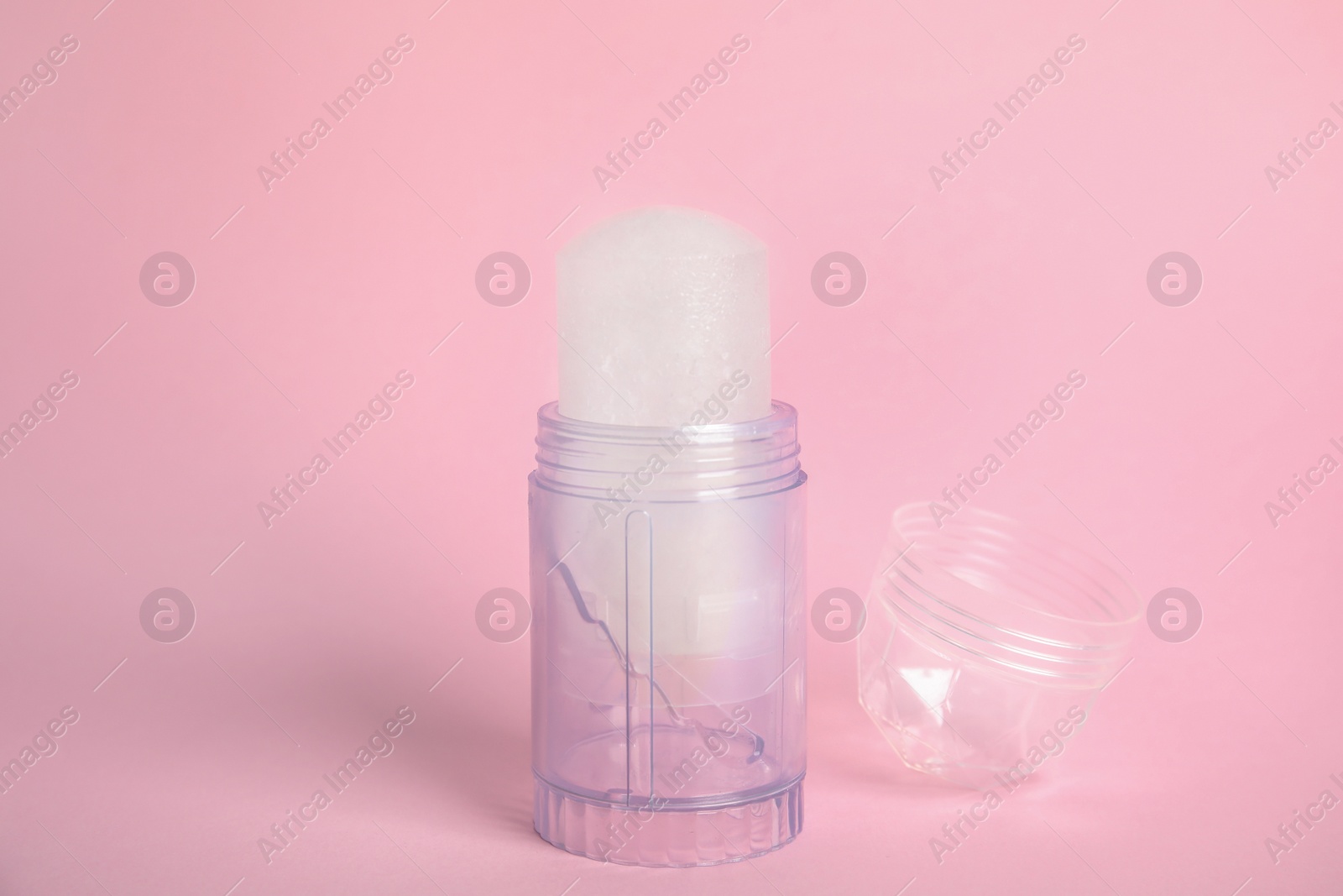 Photo of Natural crystal alum stick deodorant and cap on pink background