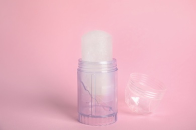 Photo of Natural crystal alum stick deodorant and cap on pink background