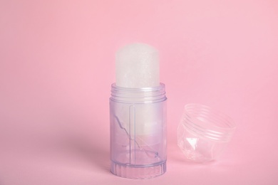 Natural crystal alum stick deodorant and cap on pink background