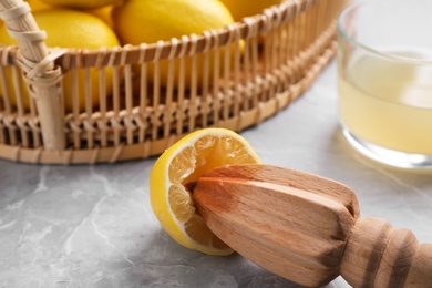 Photo of Wooden reamer and squeezed lemon on marble table, closeup