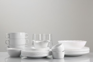 Photo of Set of many clean dishware and glasses on light table. Space for text