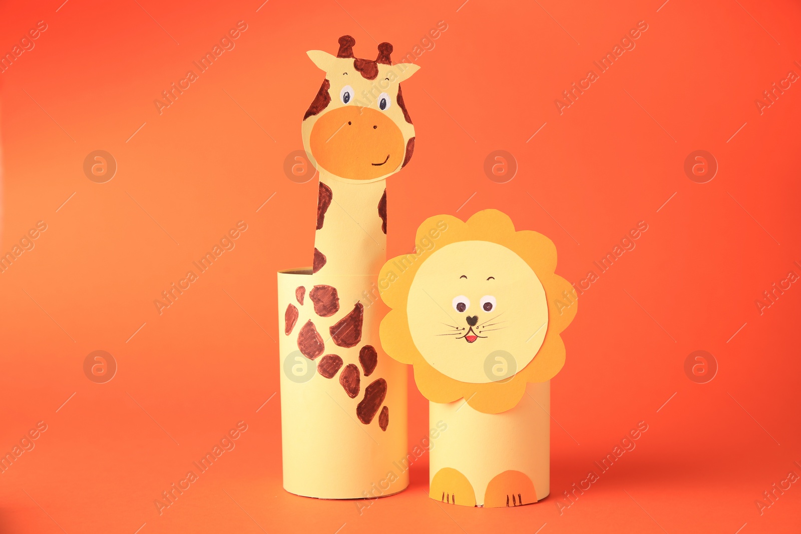 Photo of Toy giraffe and lion made from toilet paper hubs on orange background. Children's handmade ideas