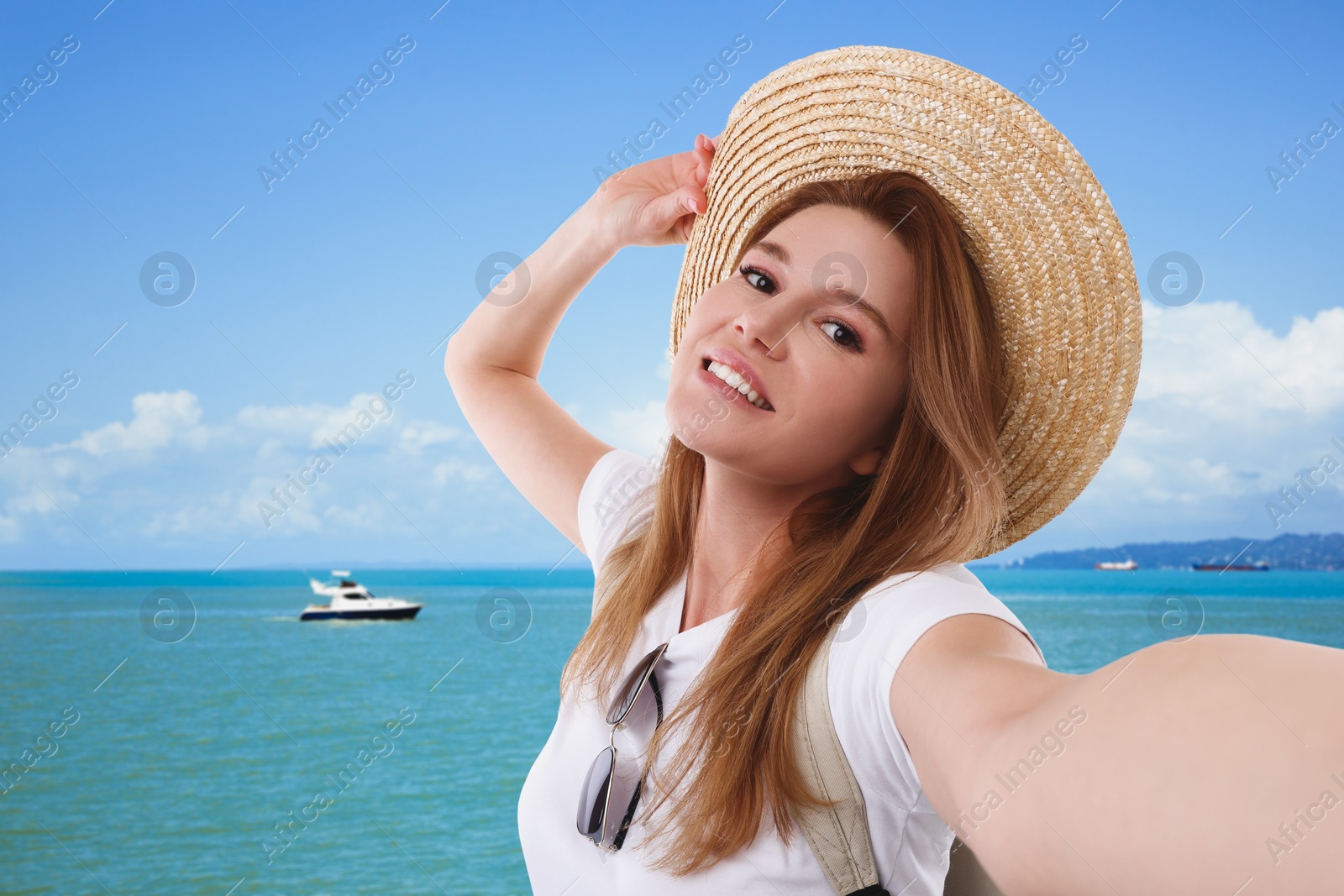 Image of Beautiful woman in straw hat taking selfie near sea