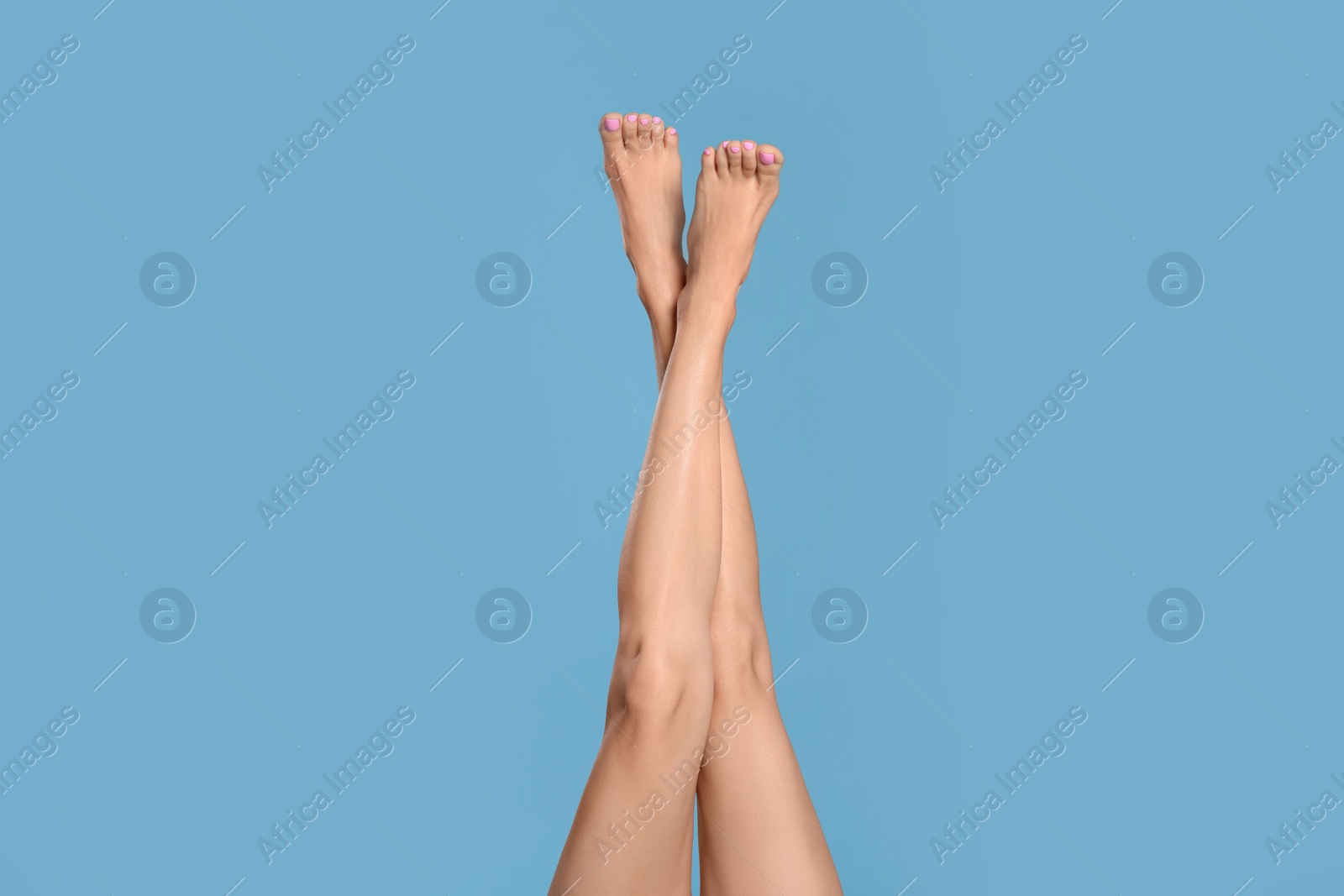 Photo of Woman with beautiful long legs on light blue background, closeup