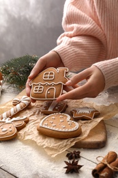 Photo of Woman holding delicious homemade Christmas cookie at wooden table, closeup