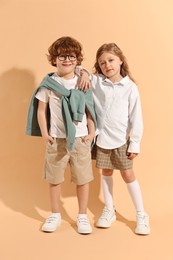 Photo of Fashion concept. Stylish children on pale orange background