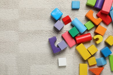 Colorful wooden building blocks on carpet, flat lay. Space for text