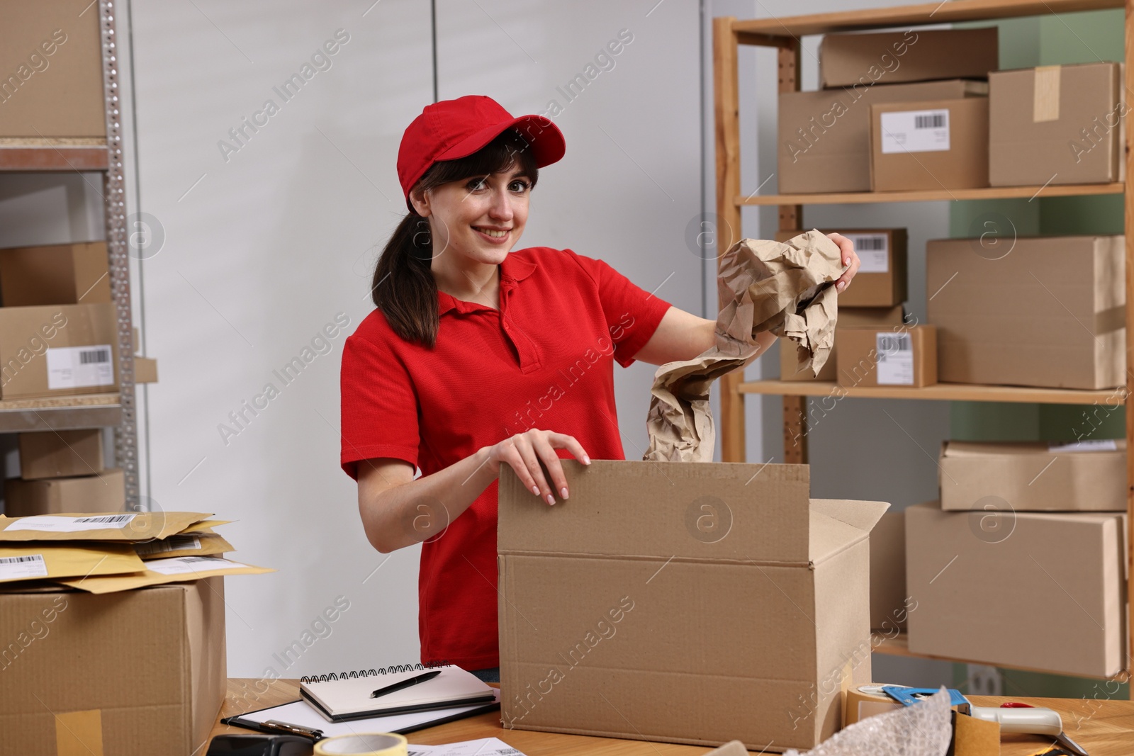 Photo of Post office worker packing parcel at wooden table indoors