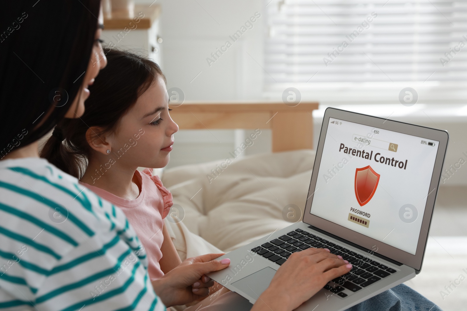 Photo of Mom installing parental control on laptop at home. Child safety