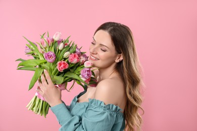 Photo of Happy young woman with bouquet of beautiful tulips on pink background