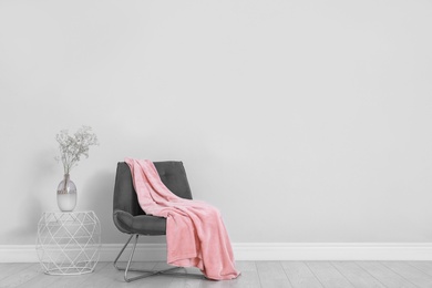 Photo of Stylish room interior with comfortable chair and plaid near white wall. Space for text