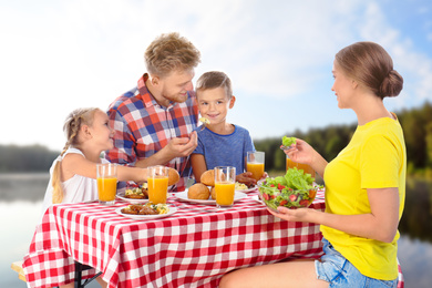 Happy family having picnic at table in park