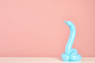 Photo of Snake figure made of modelling balloon on table against color background. Space for text