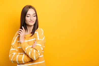 Portrait of pretty young woman with gorgeous chestnut hair on yellow background, space for text