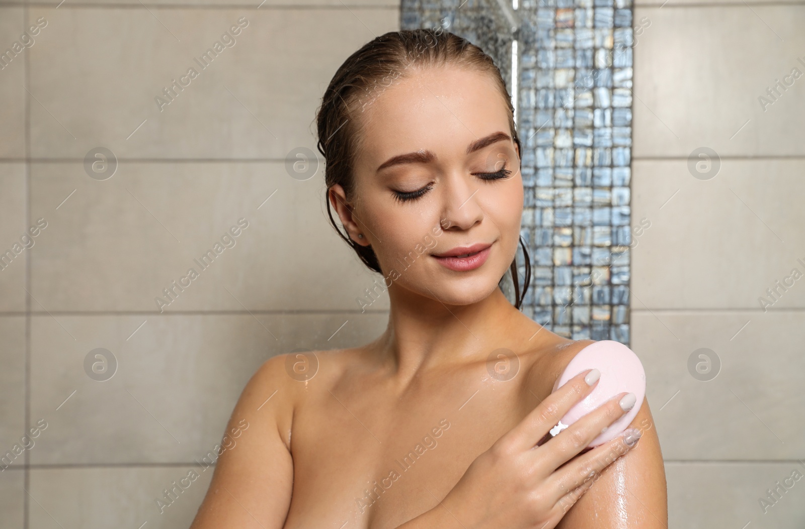 Photo of Beautiful young woman taking shower with soap in bathroom