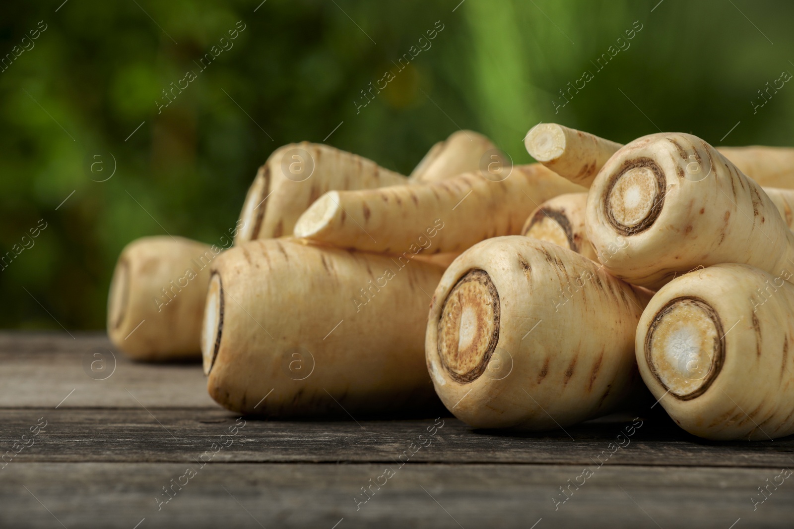 Photo of Delicious fresh ripe parsnips on wooden table outdoors, space for text
