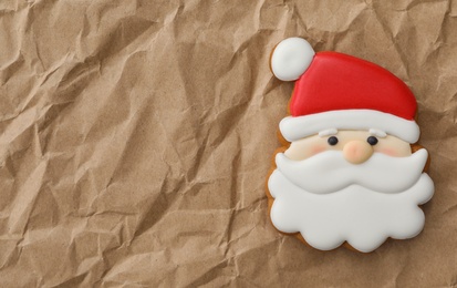 Photo of Christmas Santa Claus shaped gingerbread cookie on crumpled parchment, top view. Space for text