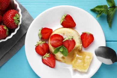 Tasty vanilla fondant with white chocolate and strawberries on light blue wooden table, flat lay