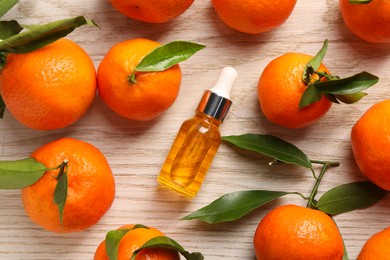 Photo of Bottle of tangerine essential oil and fresh fruits on white wooden table, flat lay