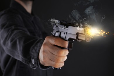 Man shooting handgun on black background, closeup