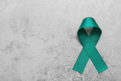 Photo of Teal awareness ribbon on grey background, top view with space for text. Symbol of social and medical issues