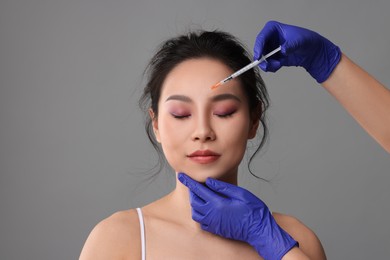 Woman getting facial injection on grey background