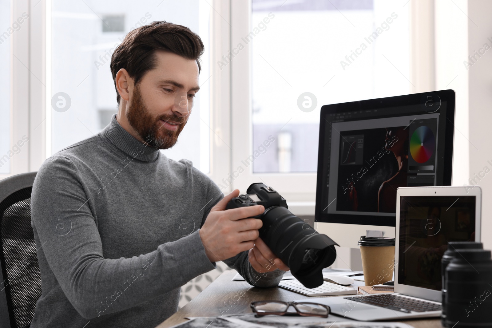 Photo of Professional photographer with digital camera at table in office