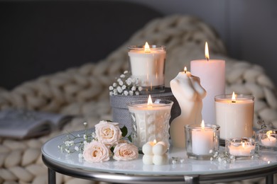 Beautiful burning candles and flowers on table indoors
